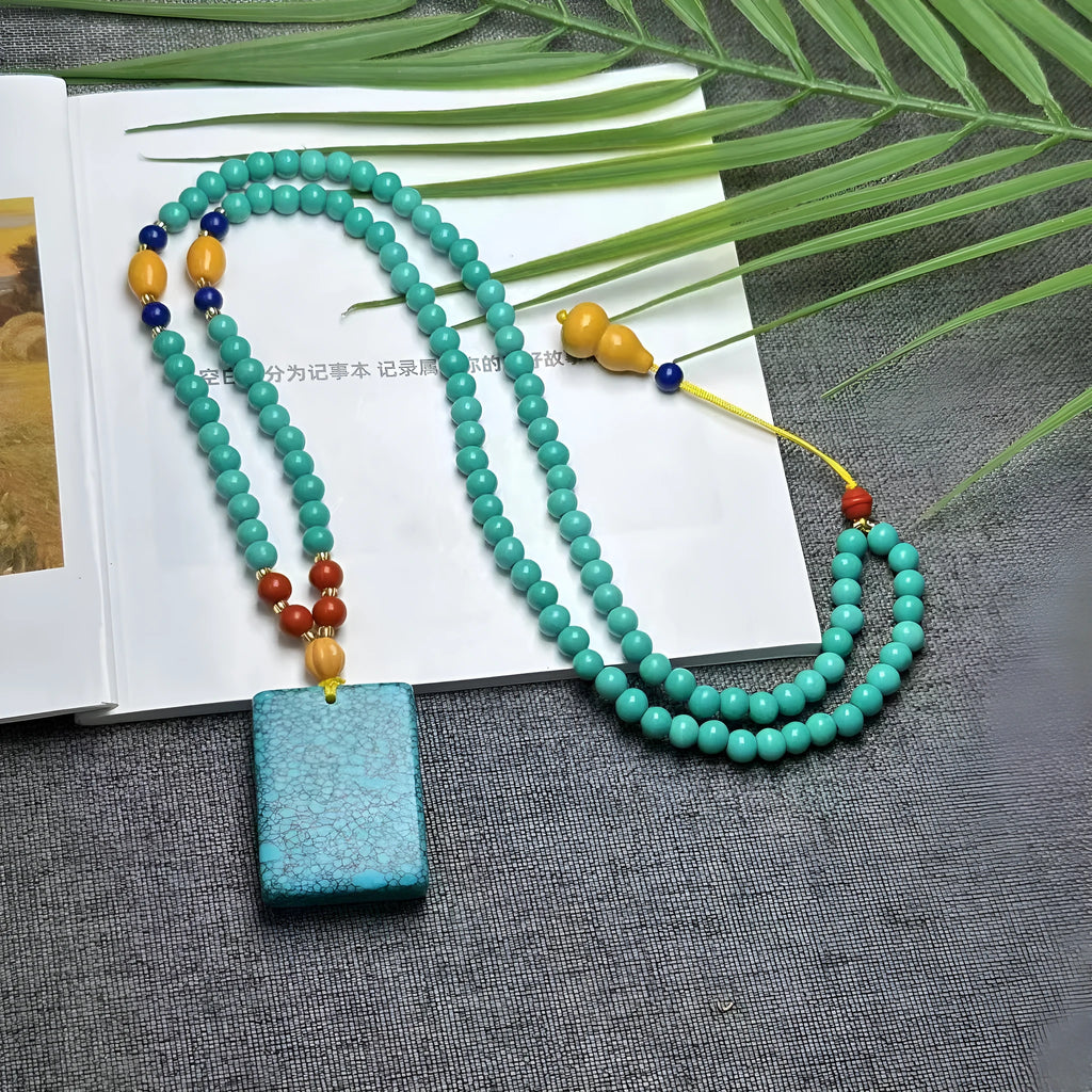 Turquoise hand-woven mesh flower lucky pendant on a long, adjustable ball bead necklace chain.