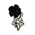 Black one-piece swimsuit with three-dimensional white floral pattern on a mannequin.