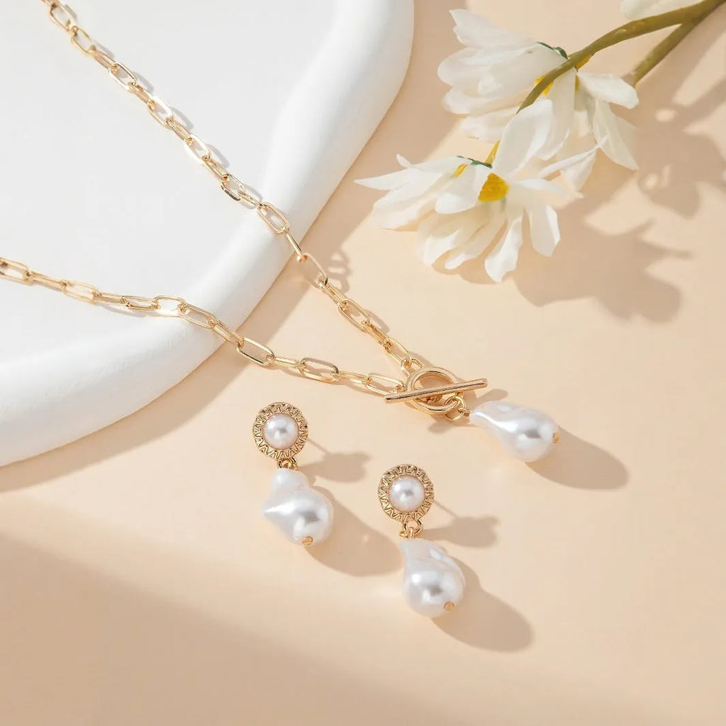 Gold tone baroque pearl pendant necklace and matching ear stud set on white background