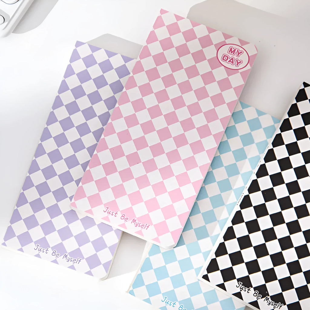 Ins style A5 grid notebook open on a desk, showing grid paper and one of twelve colourful cover designs like pineapple or checkerboard.