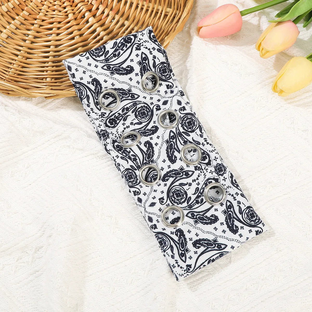 A black polyester exercise hair band with a hollow metal decorative centrepiece.