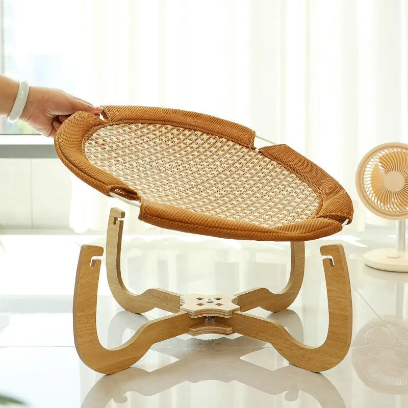 Brown woven rattan elevated hammock bed for cats and small dogs on a wooden floor.