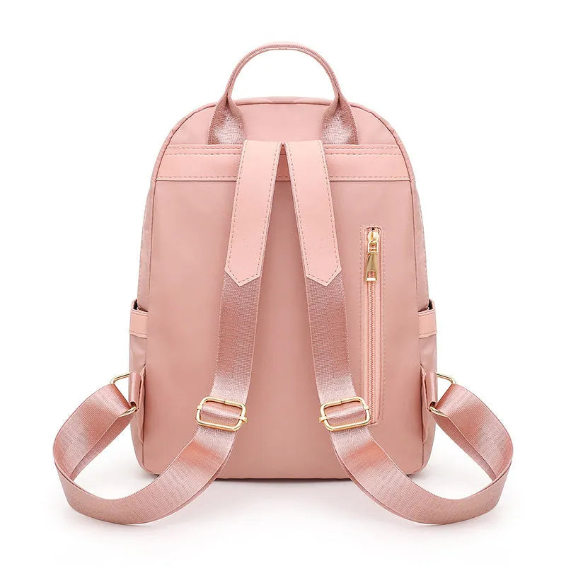 Black and pink views of a women's casual nylon backpack with double straps, a soft handle, and an external pocket.