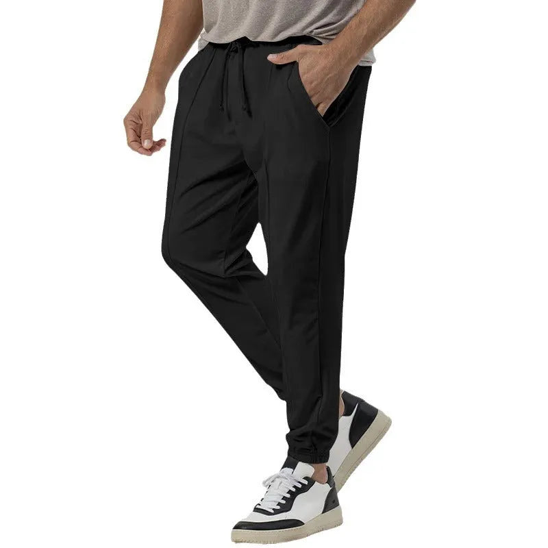 Man wearing grey straight-leg tapered casual sweatpants with an elasticated mid-waist.