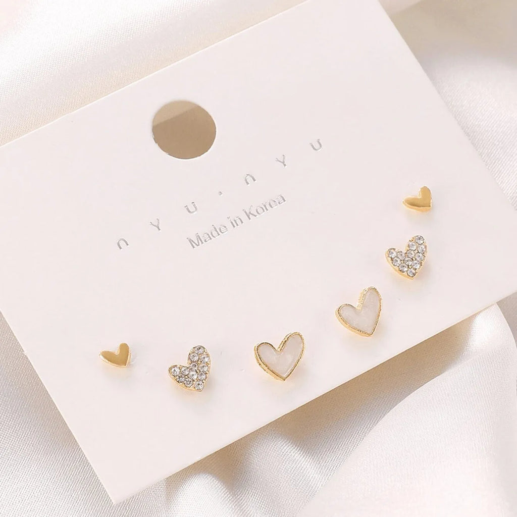 Three pairs of heart-shaped alloy earrings in gold, black, black and white, and pink electroplated colours