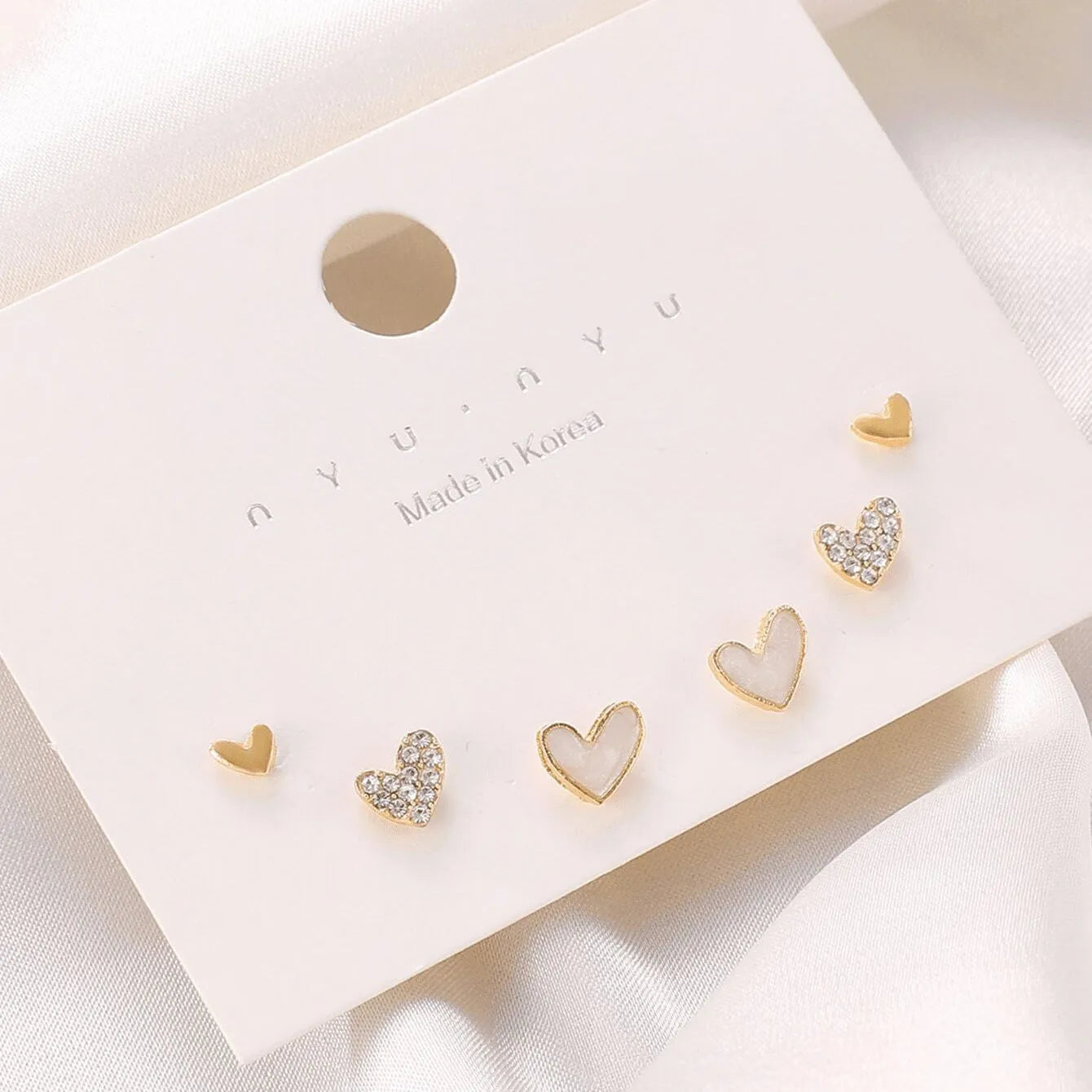 Three pairs of heart-shaped alloy earrings in gold, black, black and white, and pink electroplated colours