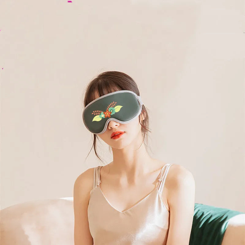 Pink portable eye SPA mask with suede shell on a grey background, showing USB port.