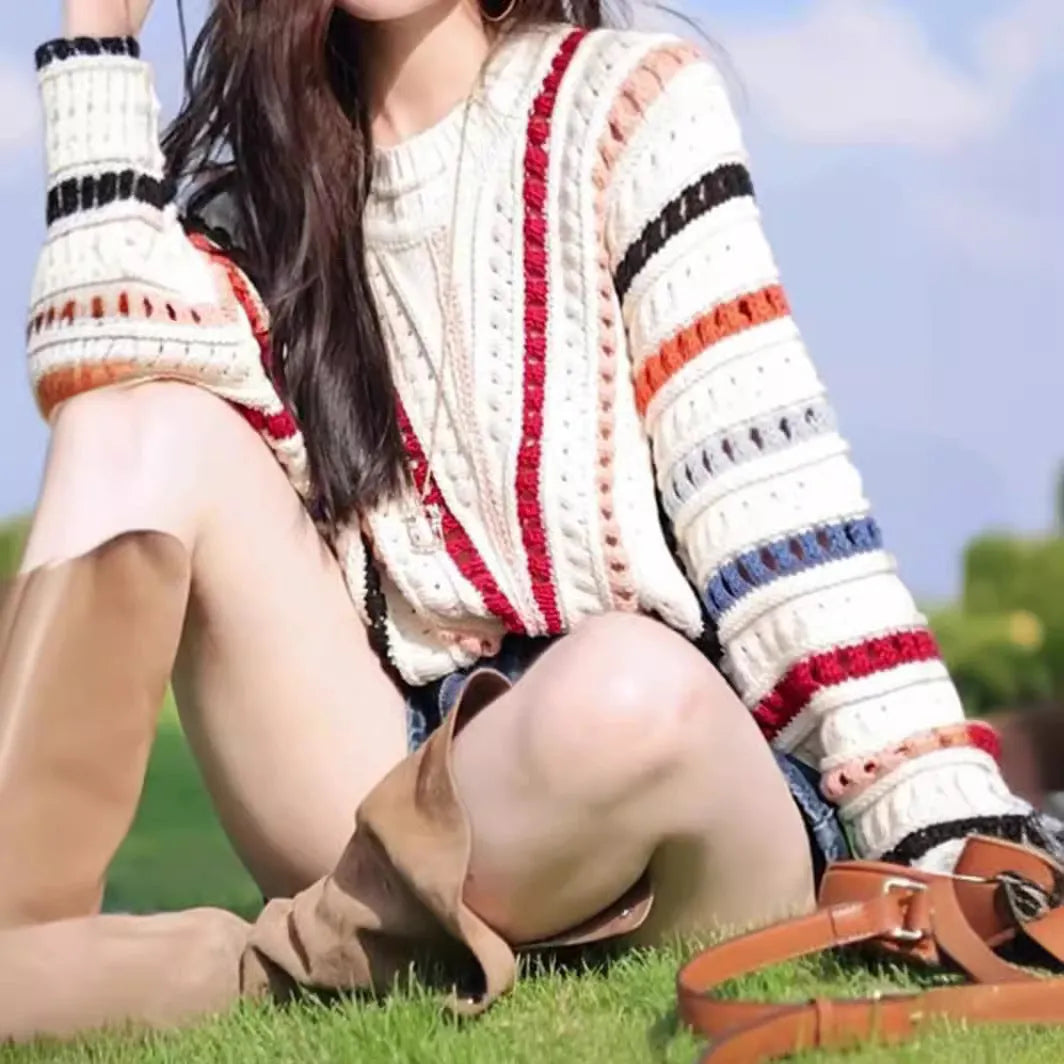 Colourful rainbow striped loose fit pullover sweater with batwing sleeves on a neutral background.