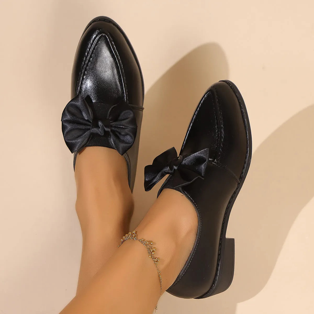 Women's casual leather shoes with a decorative bow on a pointed toe, showcasing a rubber sole.