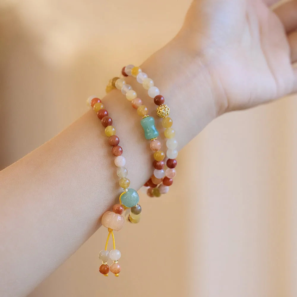 Handmade women's Jinsi Jade bracelet with three pumpkin beads and tassel on a wrist.