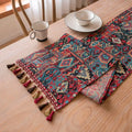 Nordic jacquard bouquet pattern table runner with tassel trim in dark blue on a dining table.