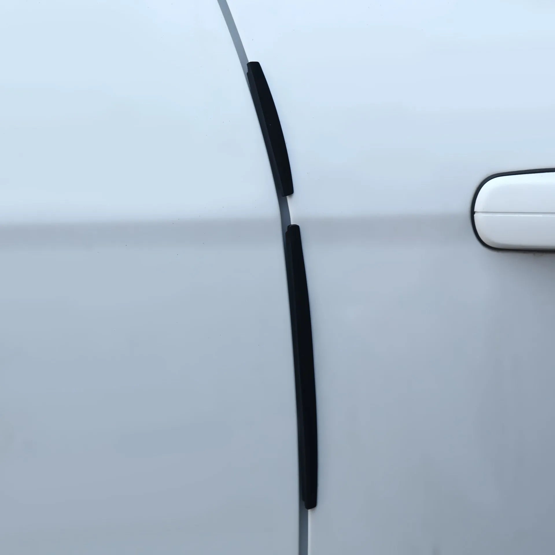 Solid white plastic car door edge anti-collision strip on a vehicle door.