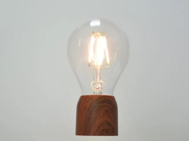 Magnetic levitation floating LED light bulb above an imitation wood base.
