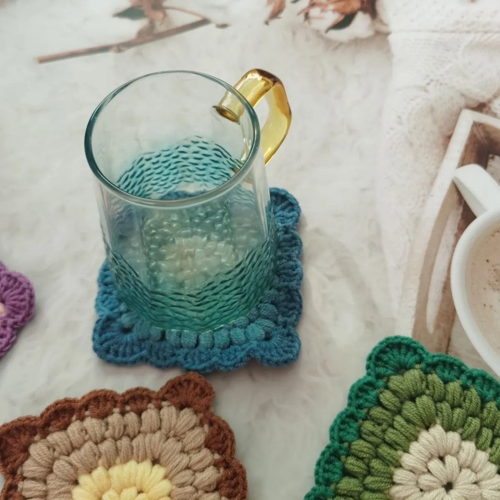 Crocheted wool cup placemat with grandmother lattice pattern in a choice of four colours.