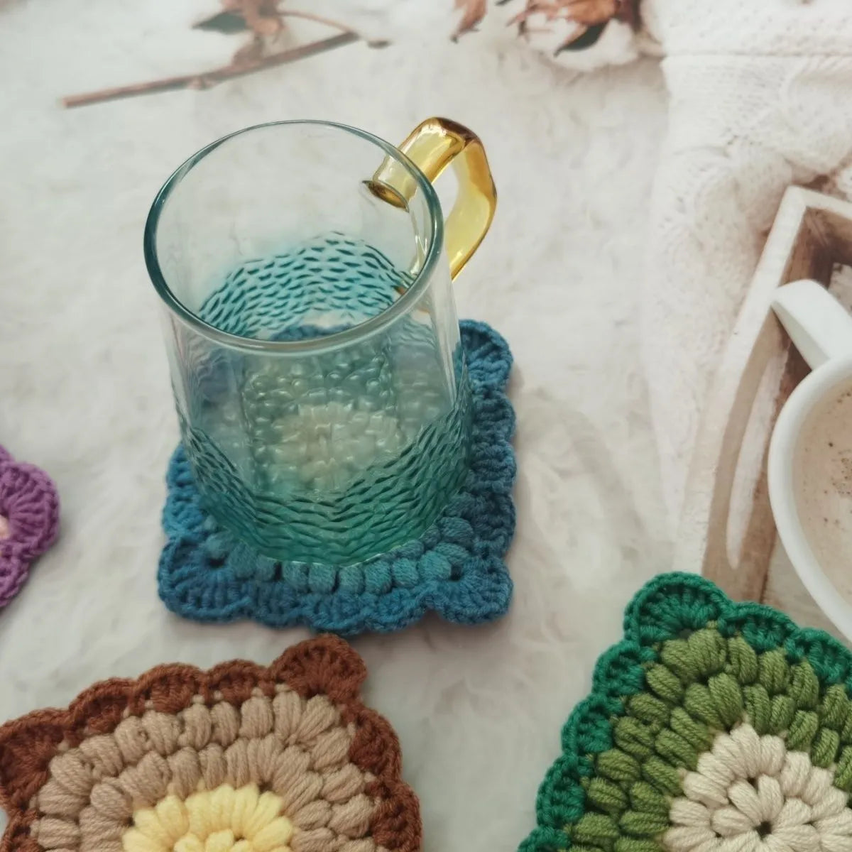 Crocheted wool cup placemat with grandmother lattice pattern in a choice of four colours.