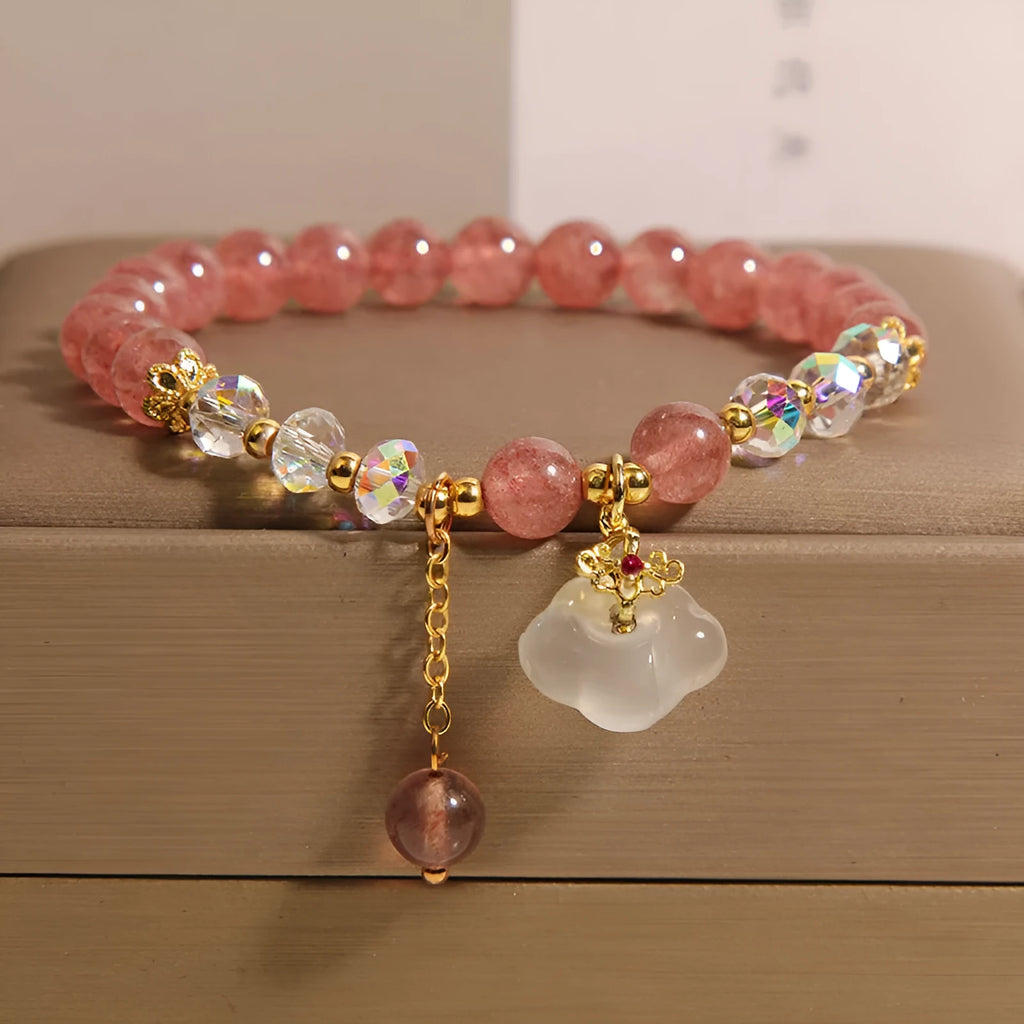 Women's bracelet with strawberry quartz and white agate beads and metal auspicious cloud charms on a white background.