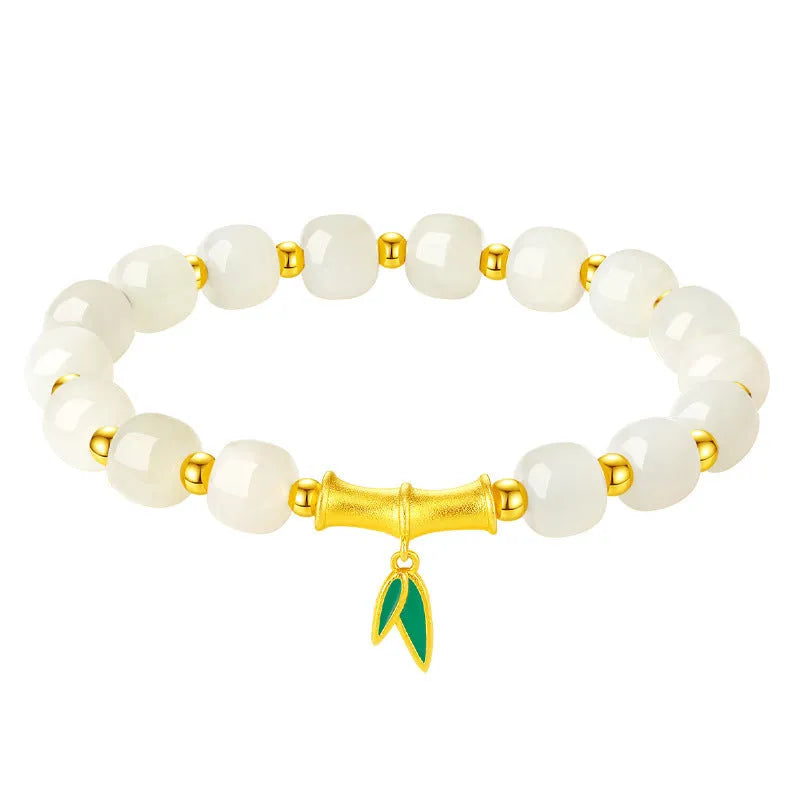 Women's bracelet with Hetian jade bead and sterling silver bamboo leaf charm on a wrist.