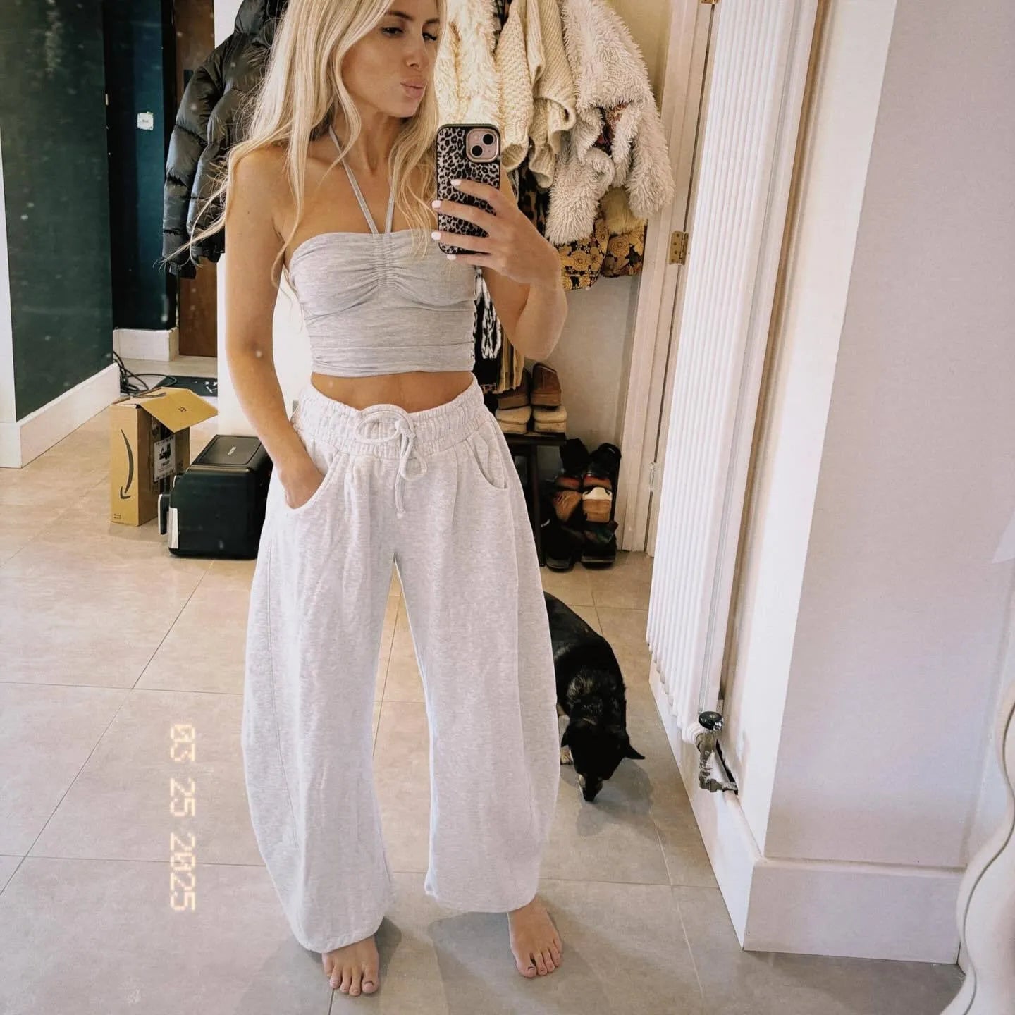 Woman wearing loose light grey cropped sweatpants with drawstring waist and side pockets