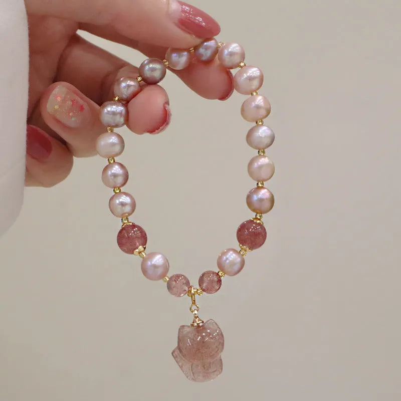 Women's light pink freshwater pearl bracelet with strawberry quartz beads and a small fox charm on an adjustable cord.