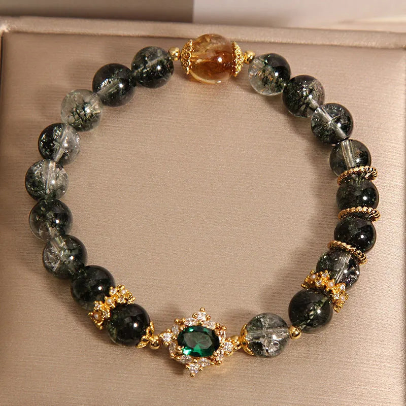 Women's green phantom quartz crystal bracelet with gold rutile needles, ruby quartz bead, pearls, and rhinestone details.