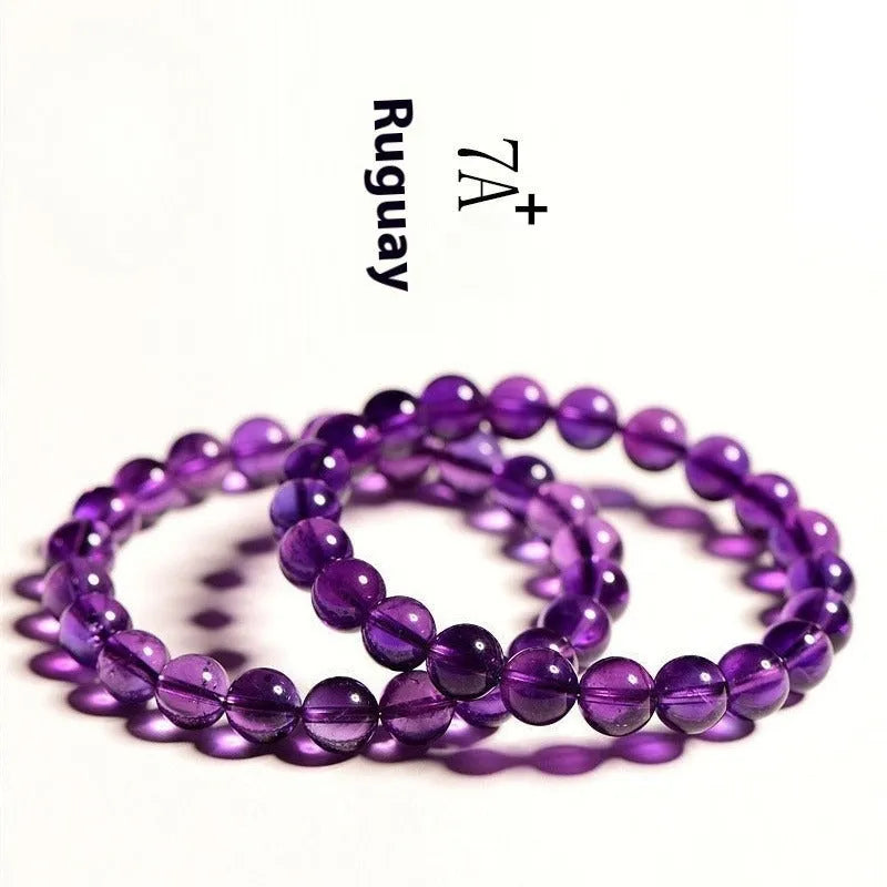 Natural polished amethyst beads scattered and strung as a bracelet on a neutral background.