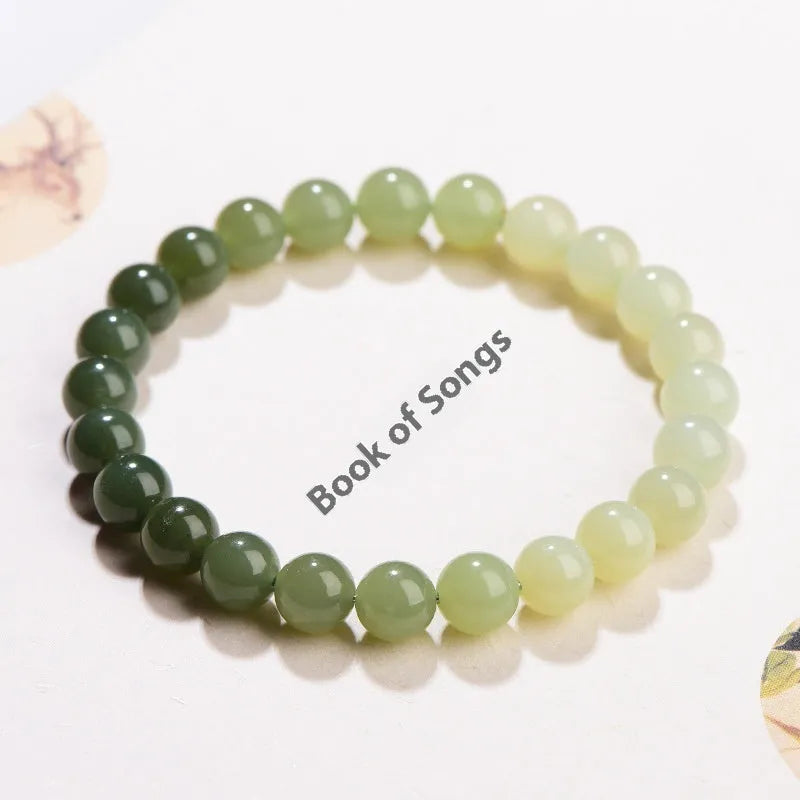 Natural clear water Hetian jade bracelet showing gradient colour on round beads and barrel beads.