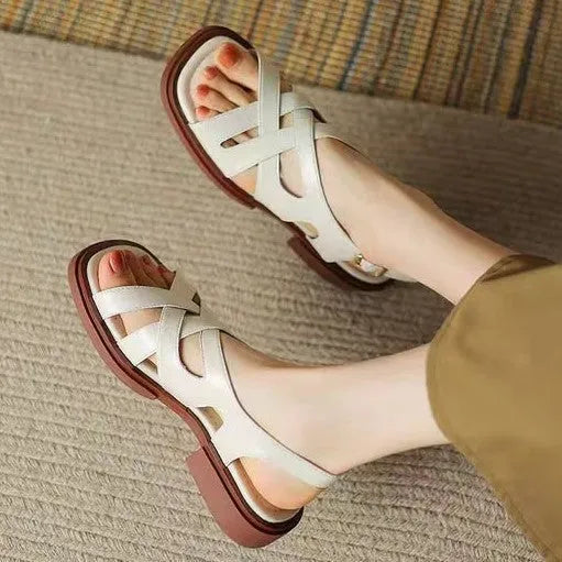 Women's black patent leather square toe beach sandals with cross strap design on a white background