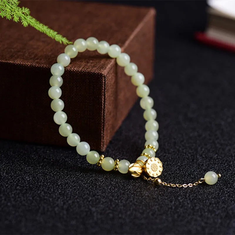 Natural Hetian jade bracelet with a carved Fu character charm on a wrist.