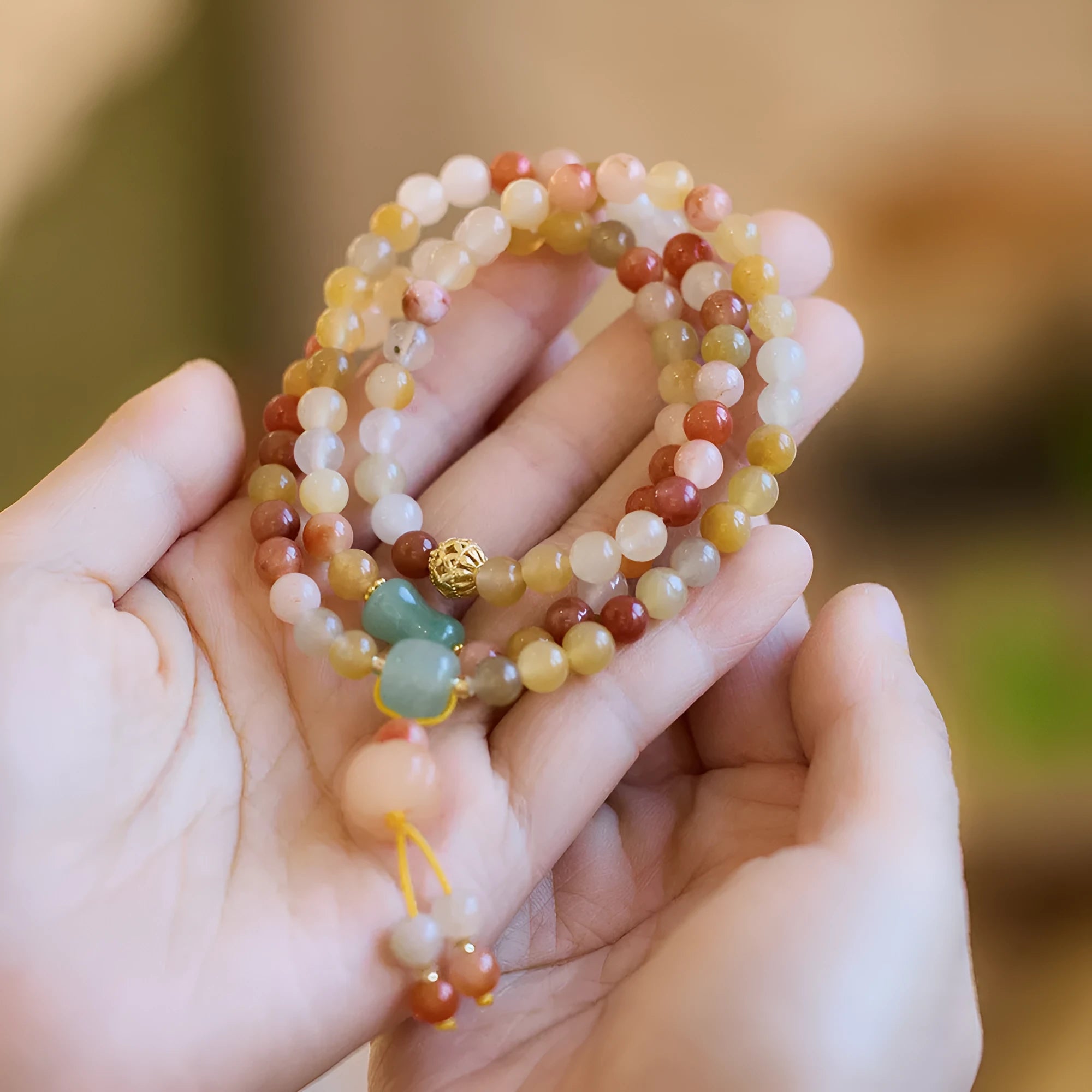 Handmade women's Jinsi Jade bracelet with three pumpkin beads and tassel on a wrist.