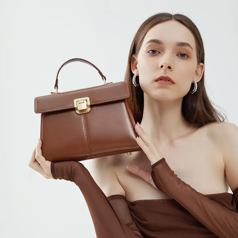 Women's black leather shoulder bag with a vachette clasp, showing its horizontal square shape and adjustable strap.