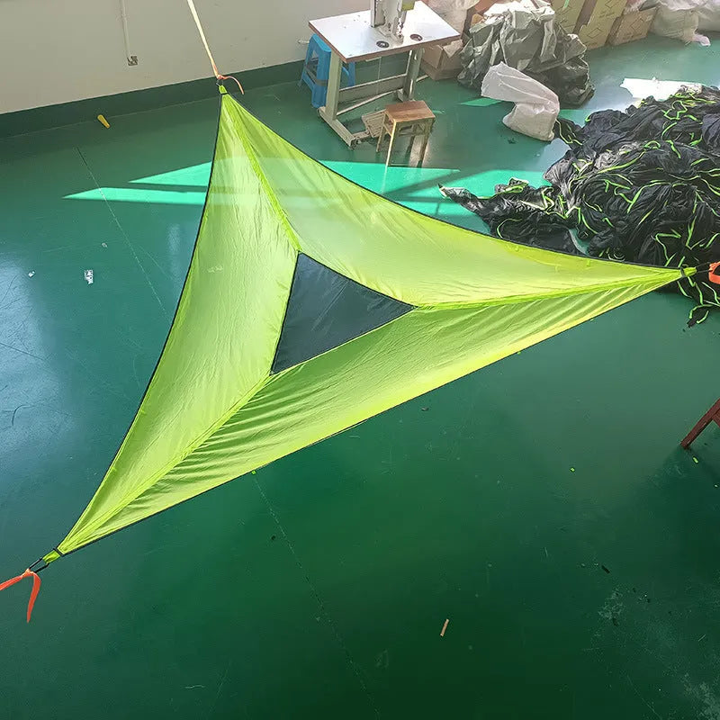 Folding portable mesh hammock in black, set up outdoors, with three supporting straps