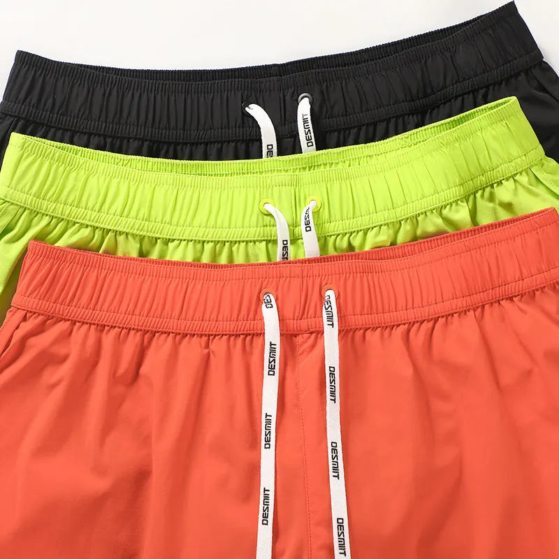 Men's loose polyester beach trousers in orange, fluorescent green, and black on a size chart