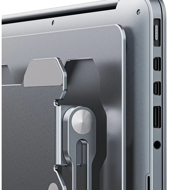 Grey portable aluminum laptop stand shown folded and in use with a silver laptop, demonstrating its adjustable angle.