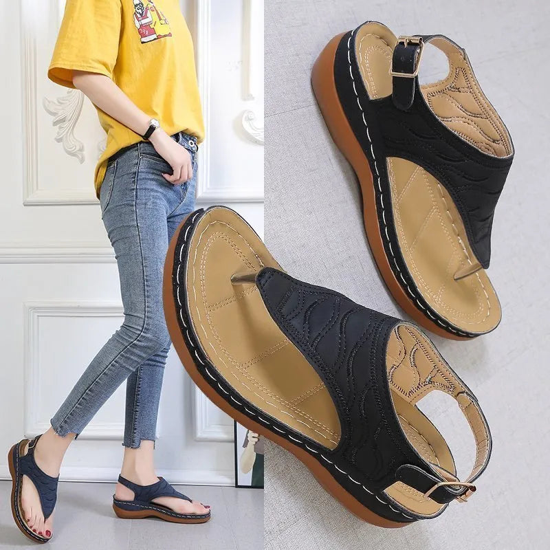 Women's black wedge heel sandals with an adjustable buckle back strap on a plain background.