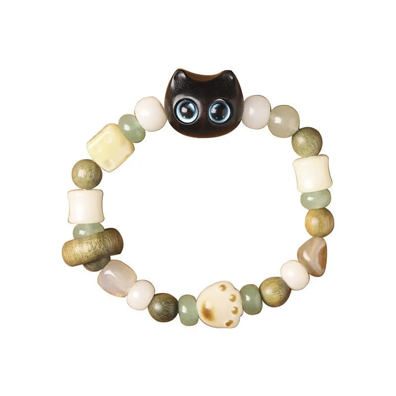 Hand-woven bracelet with jade, bodhi, and guajacwood beads, a multi-treasure cube, and a carved cat's paw charm.