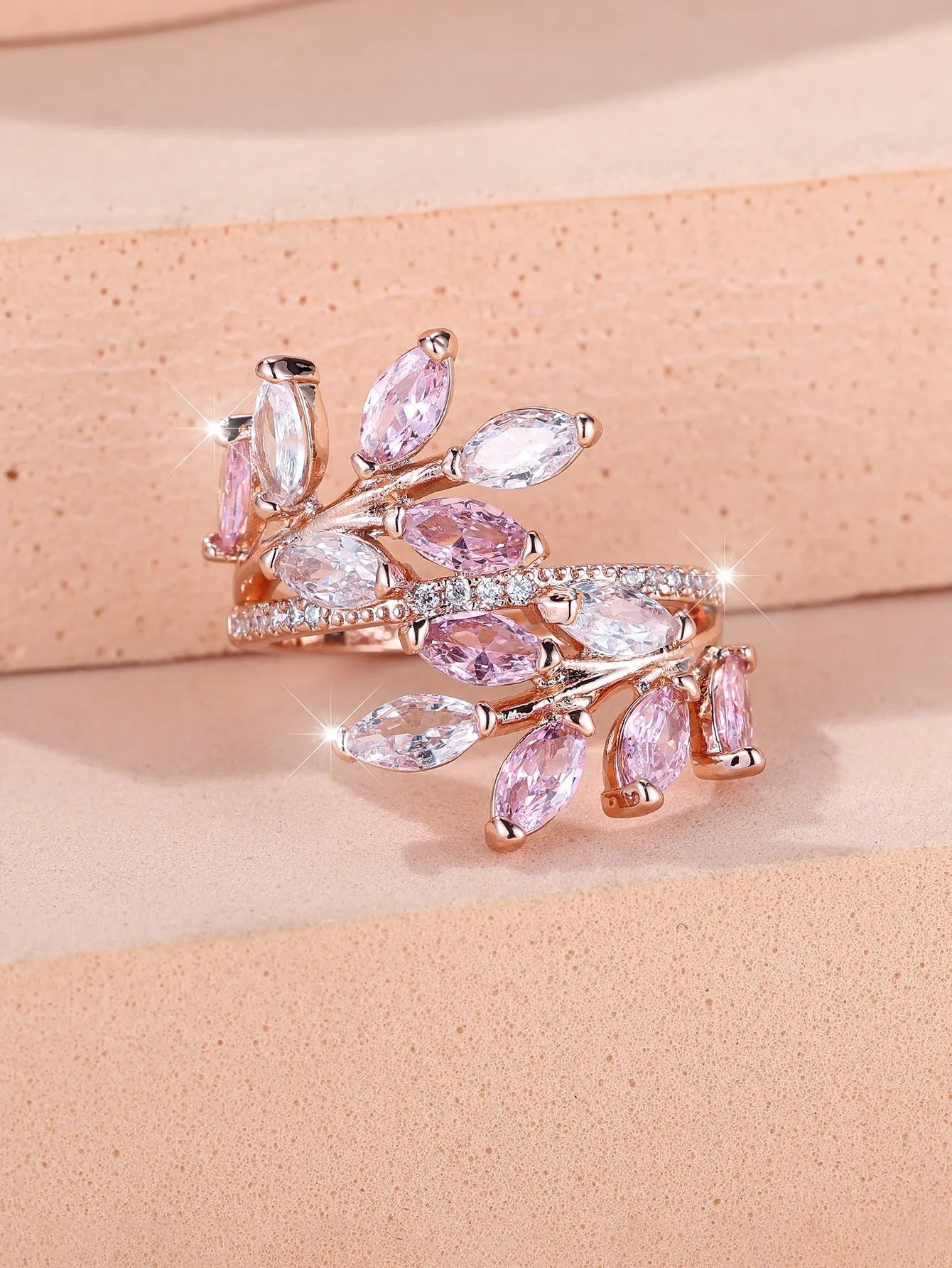 Adjustable copper leaf design ring with sparkling zircon stones on a model's finger.