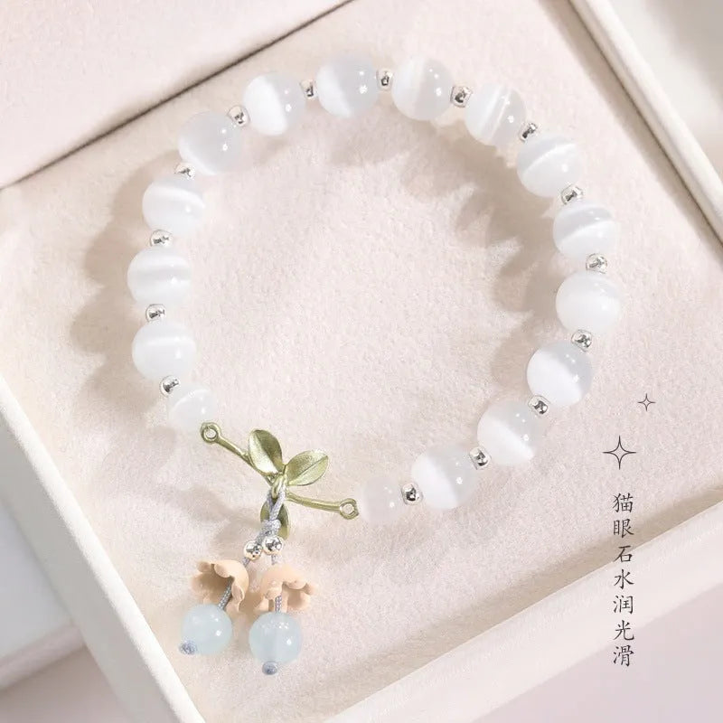 Women's opal cat's eye stone bracelet with diamond-shaped beads on wrist.