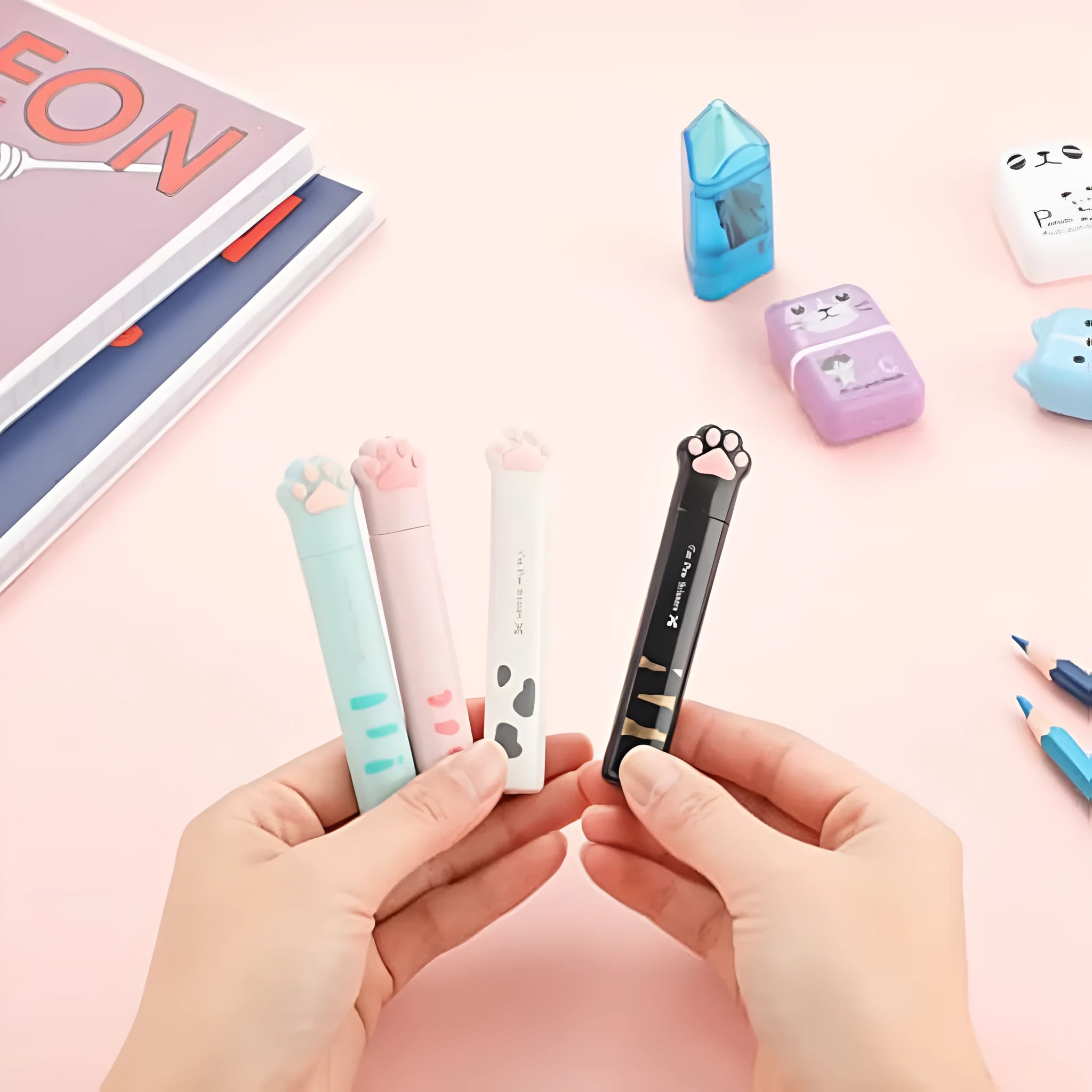Set of four mini folding scissors with cat paw handles in pink, white, black, and blue colours, shown closed.