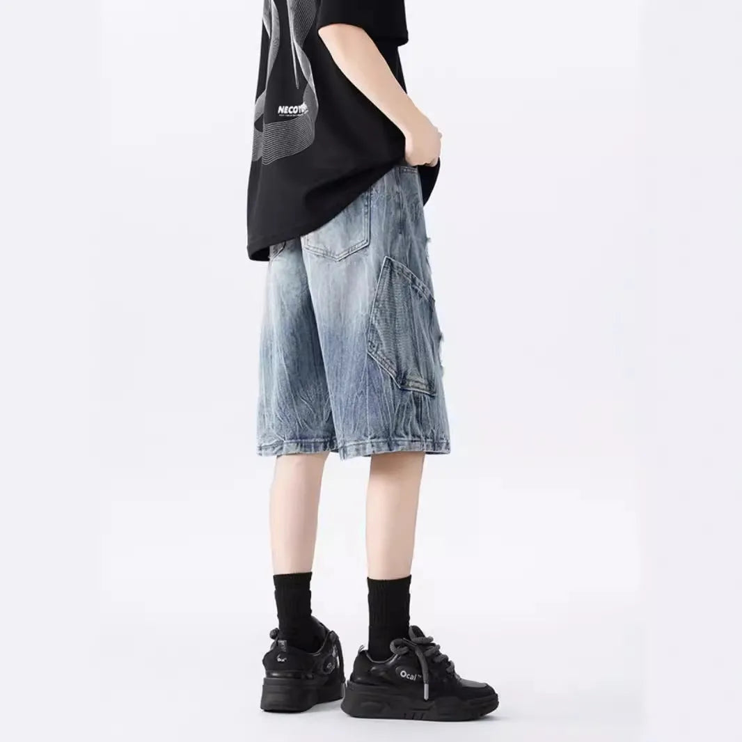 Man wearing loose-fit black denim shorts with ripped detailing and a washed vintage finish.