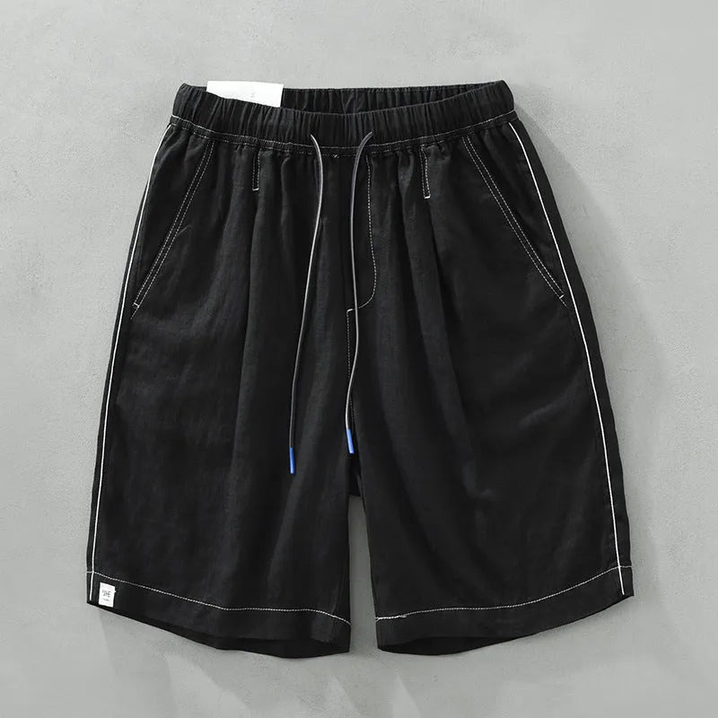 Man wearing loose green linen shorts with a drawstring waist and straight leg cut.