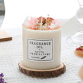 Scented aromatherapy candle with dried flower decoration on a wooden chip base.