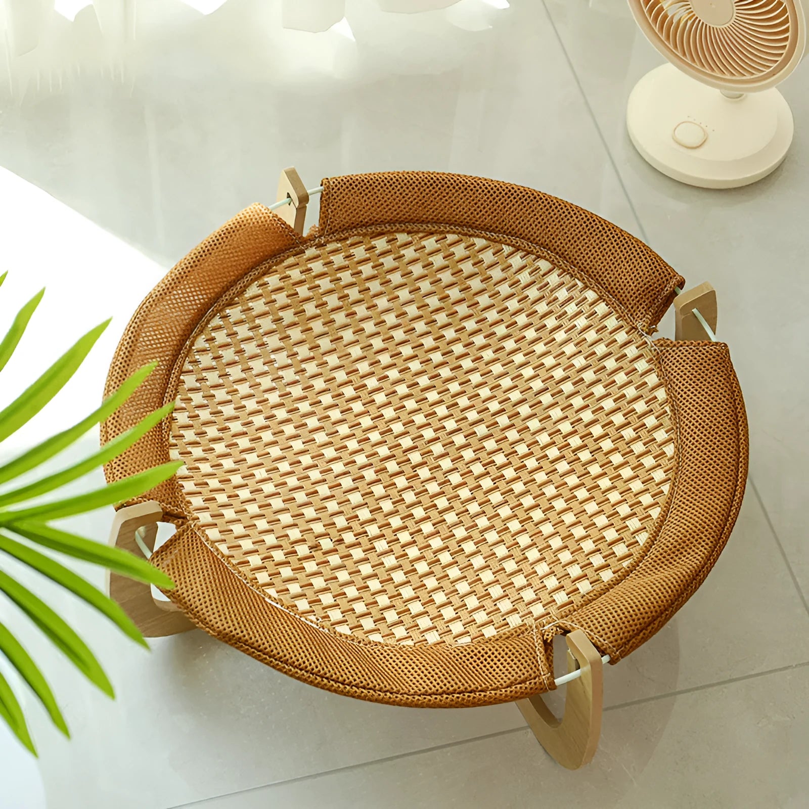 Brown woven rattan elevated hammock bed for cats and small dogs on a wooden floor.