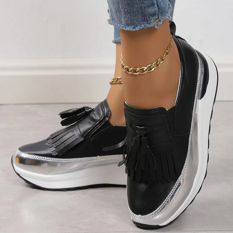 Women's black casual platform shoes with a tassel and distinctive muffin wedge heel on a white background.