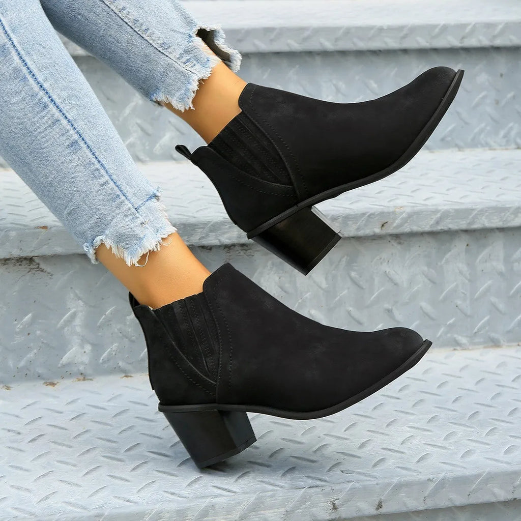 Black pointed toe women's ankle boots with a thick square low heel on a white background.