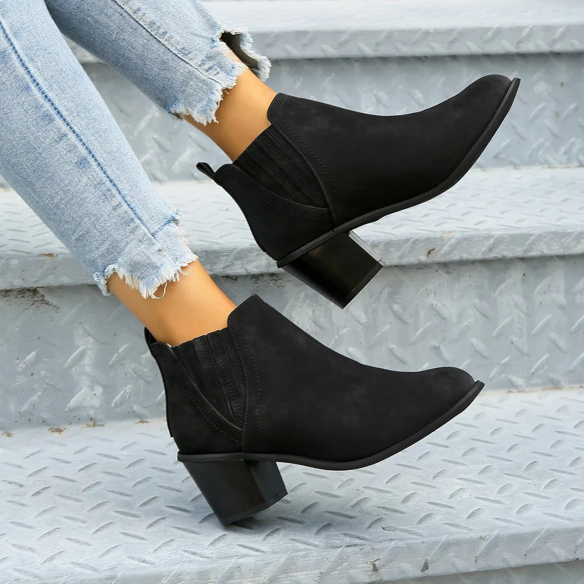 Black pointed toe women's ankle boots with a thick square low heel on a white background.