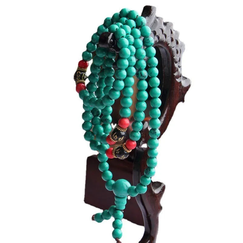 Multi-layer turquoise Tibetan bracelet with 108 round polished beads, shown in hand.
