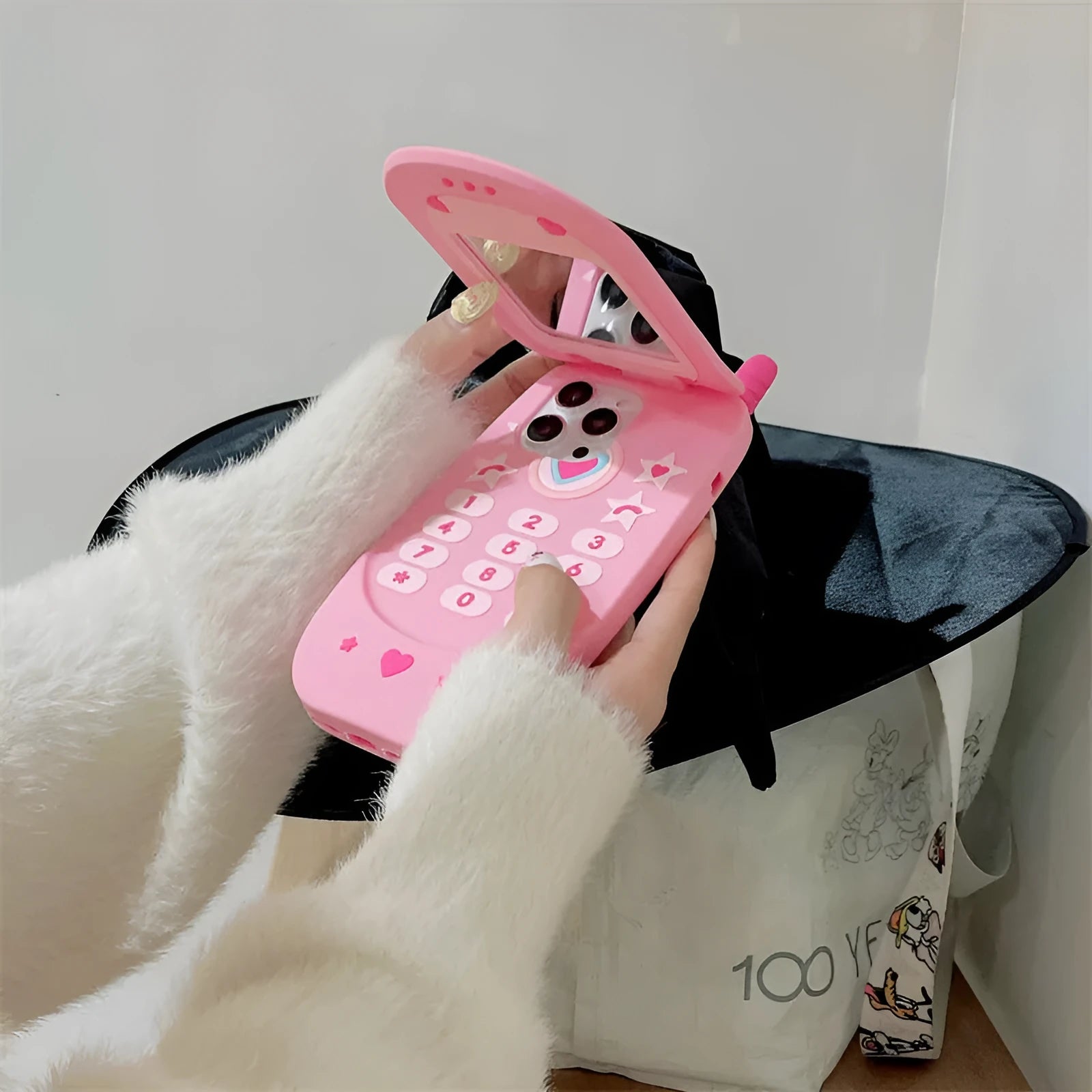 Light pink silicone iPhone case with a built-in cosmetic mirror, showing a cute cartoon design.