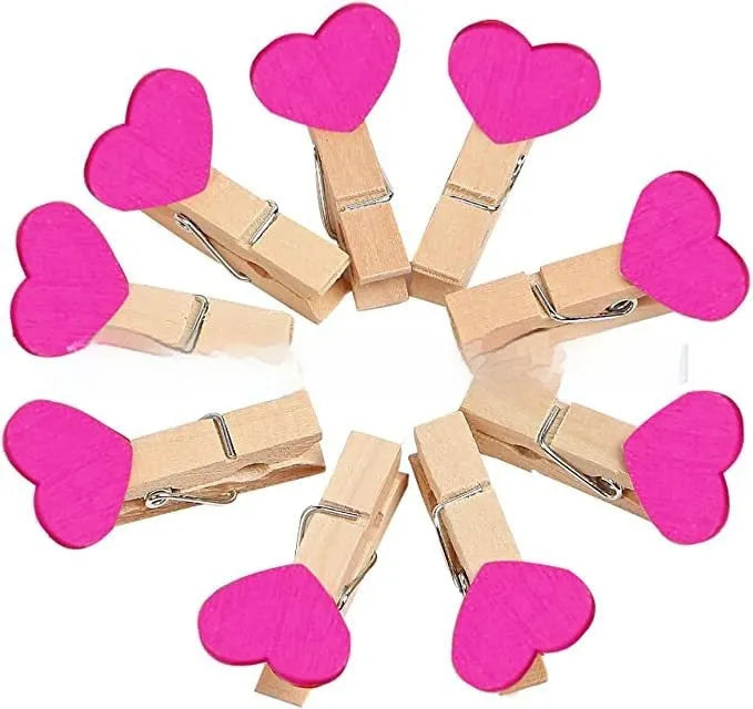 Five handmade wooden heart-shaped clips in red, white, and rose red on a surface.
