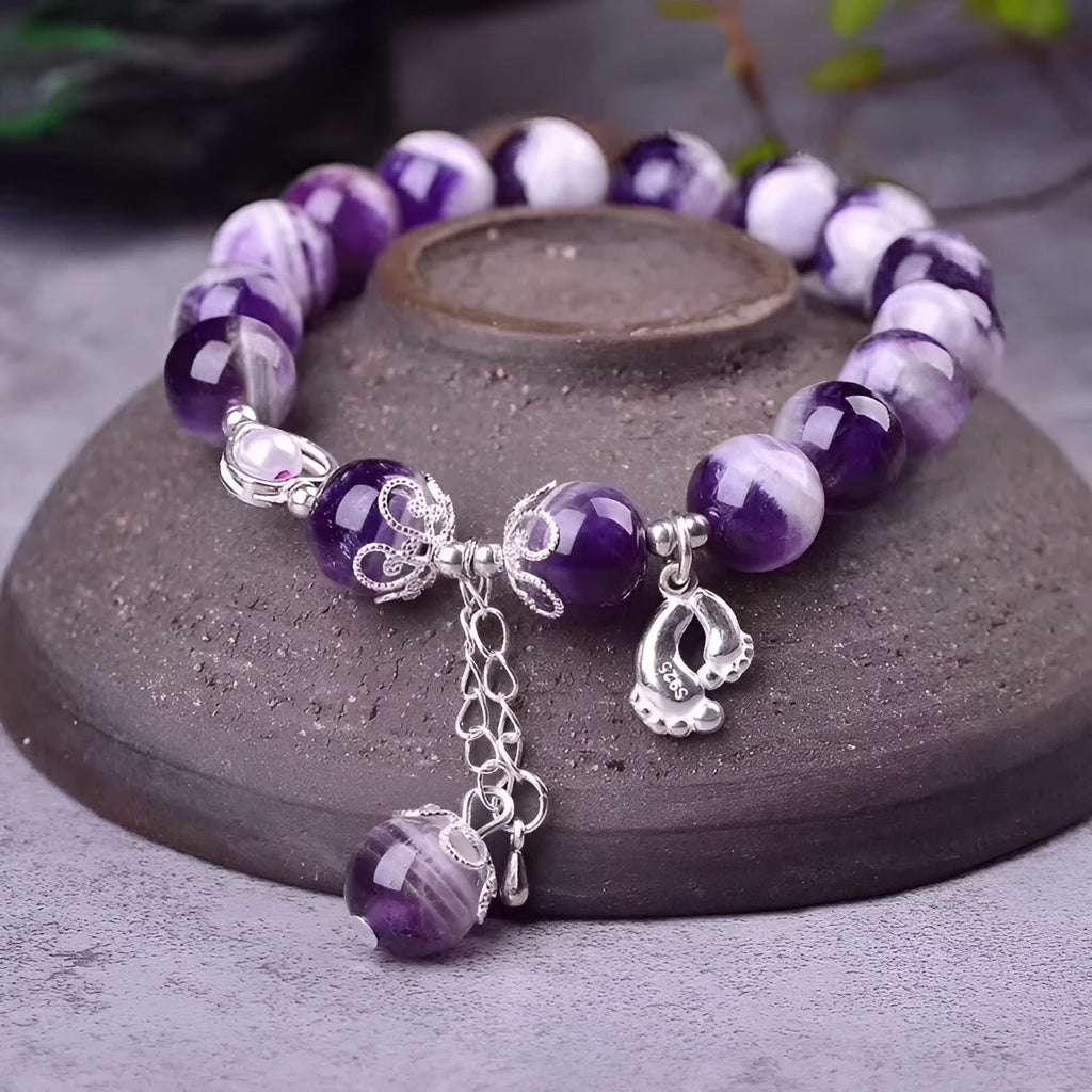Close-up of a natural amethyst bracelet with 10mm round purple beads on a wrist.