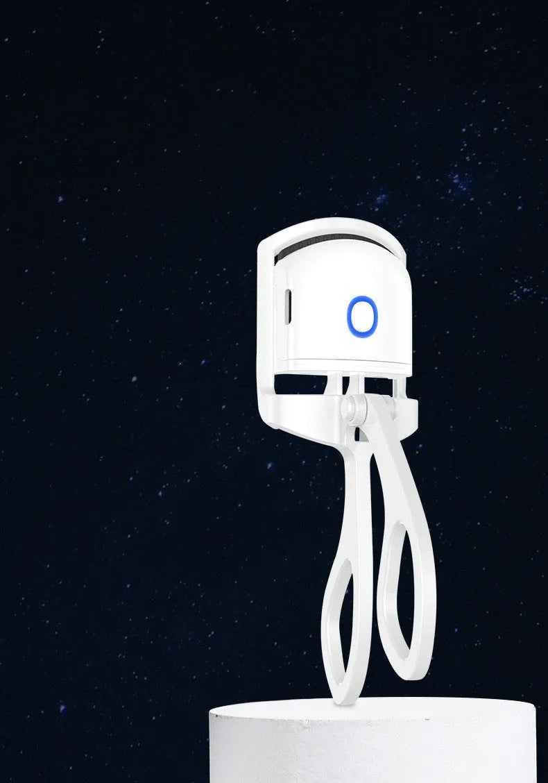 White USB rechargeable heated eyelash curler with dual temperature lights, shown next to its charging cable.